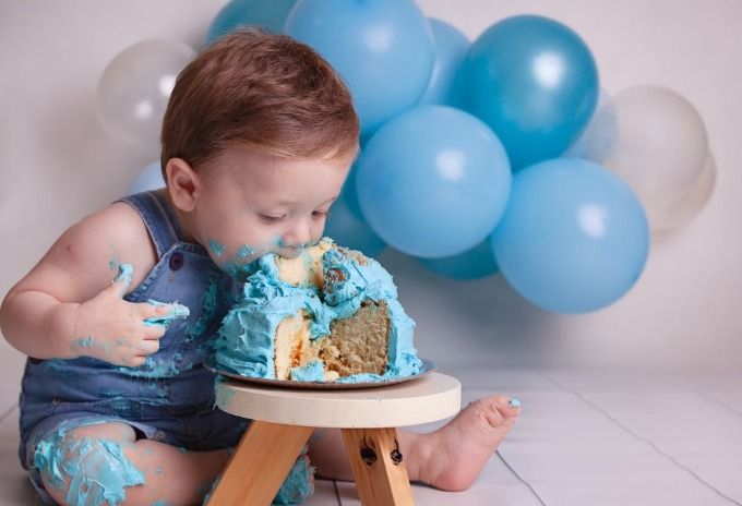 Un bebé está sentado en una mesa comiendo un pastel cubierto de glaseado azul.