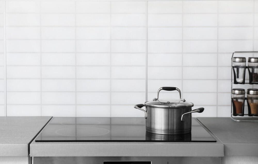 A Pot Is Sitting On Top Of An Induction Stove In A Kitchen — Lake Macquarie Designer Kitchens In Watagan Park, NSW
