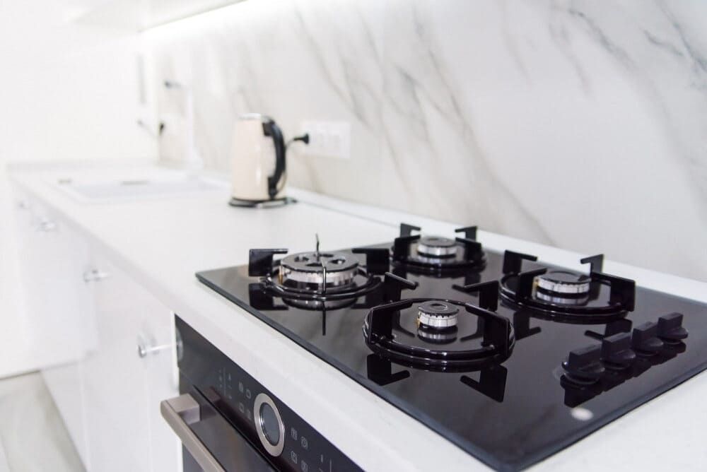 A Black Gas Stove With Four Burners In A Kitchen — Lake Macquarie Designer Kitchens In Cessnock, NSW