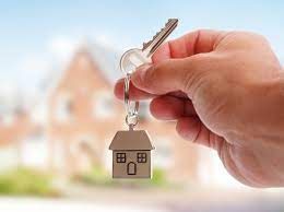 close up of home keys with house in background