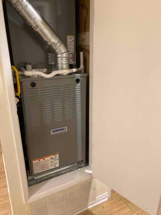 A furnace is sitting inside of a wall in a room.