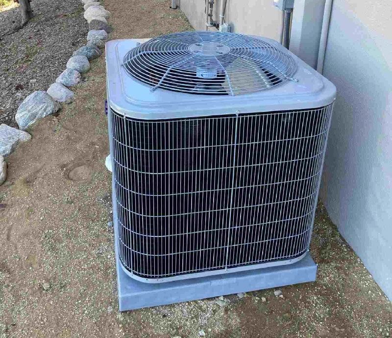 A large air conditioner is sitting on the side of a building.