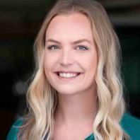 A woman with blonde hair is smiling and wearing a green shirt.