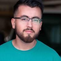 A man with a beard and glasses is wearing a green shirt.
