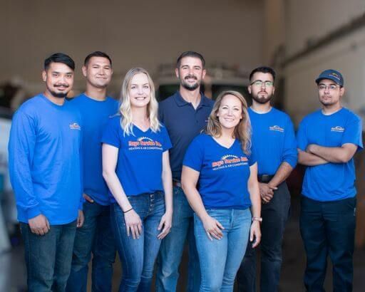 A group of people wearing blue shirts are posing for a picture.