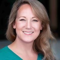 A woman in a green shirt is smiling for the camera.