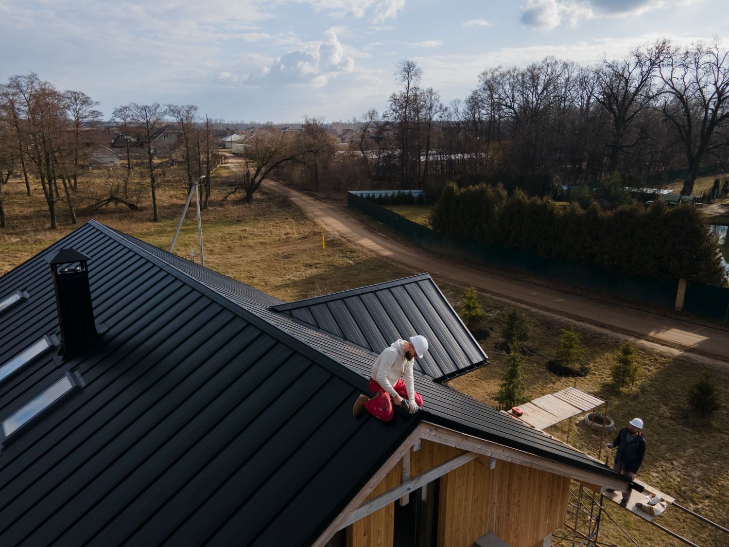 Child in pink sits on a dark roof overlooking a rural road and trees