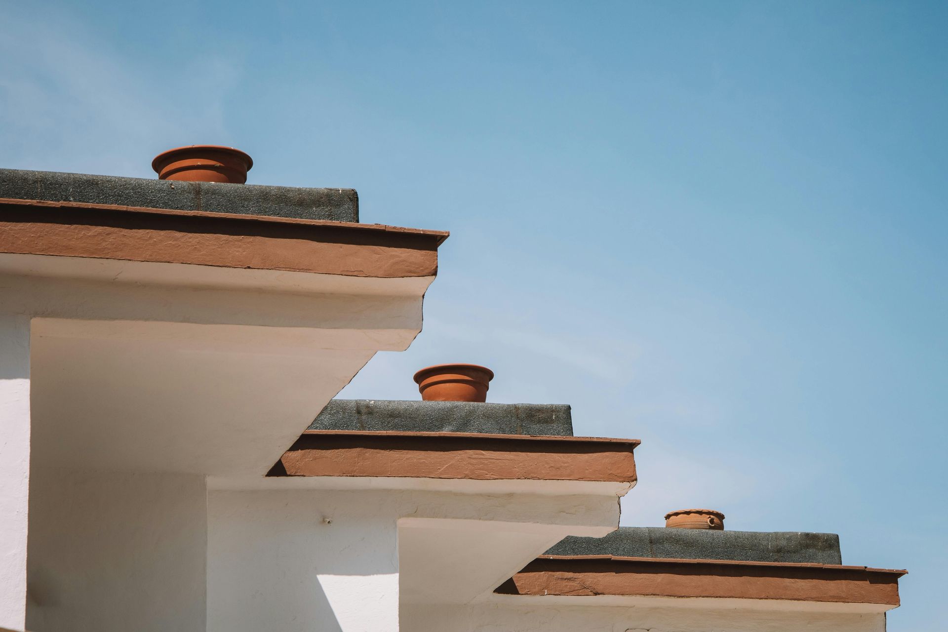 White building rooftops with terracotta chimney caps against a blue sky