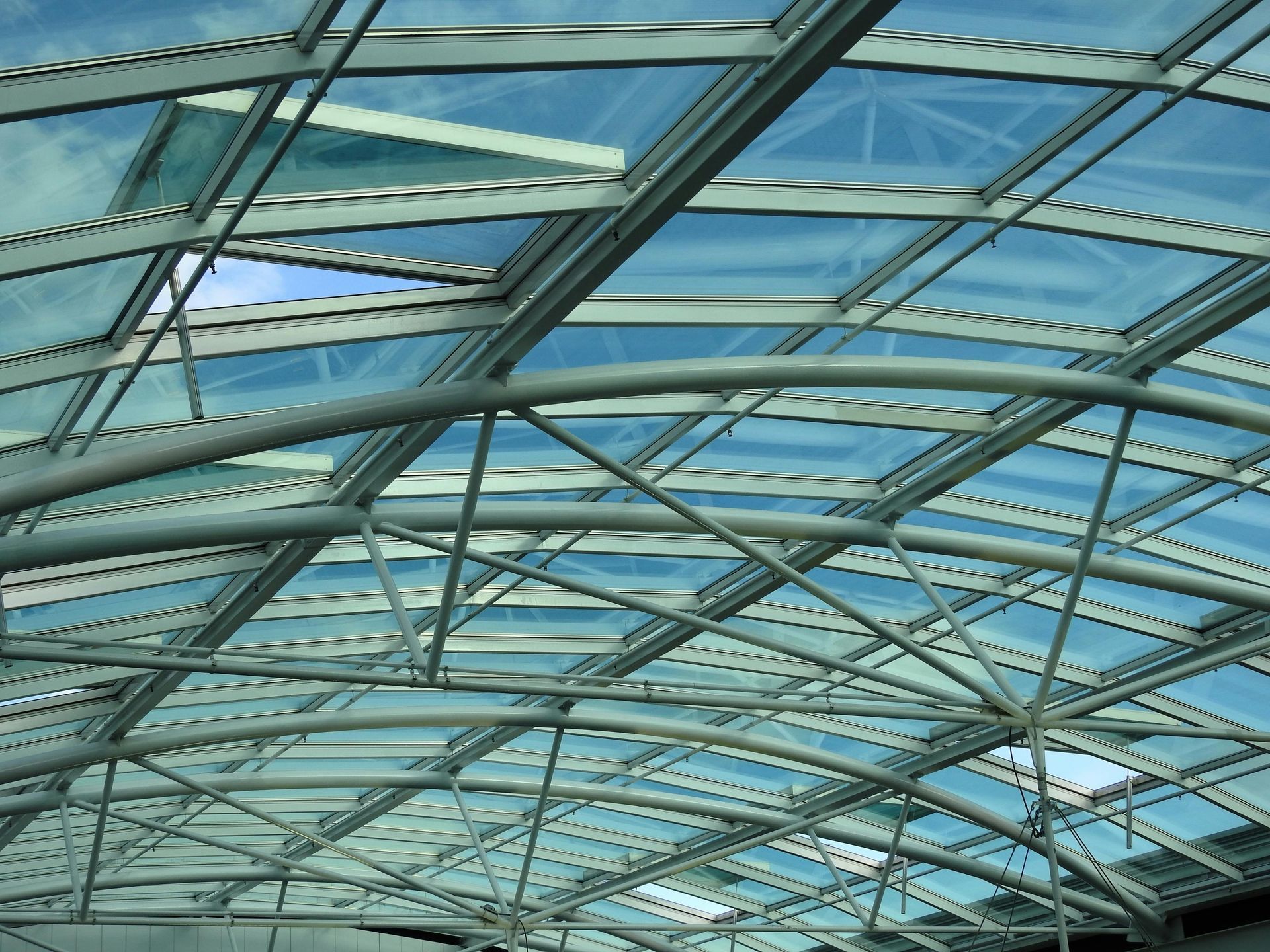 Curved glass roof with blue steel beams and skylights