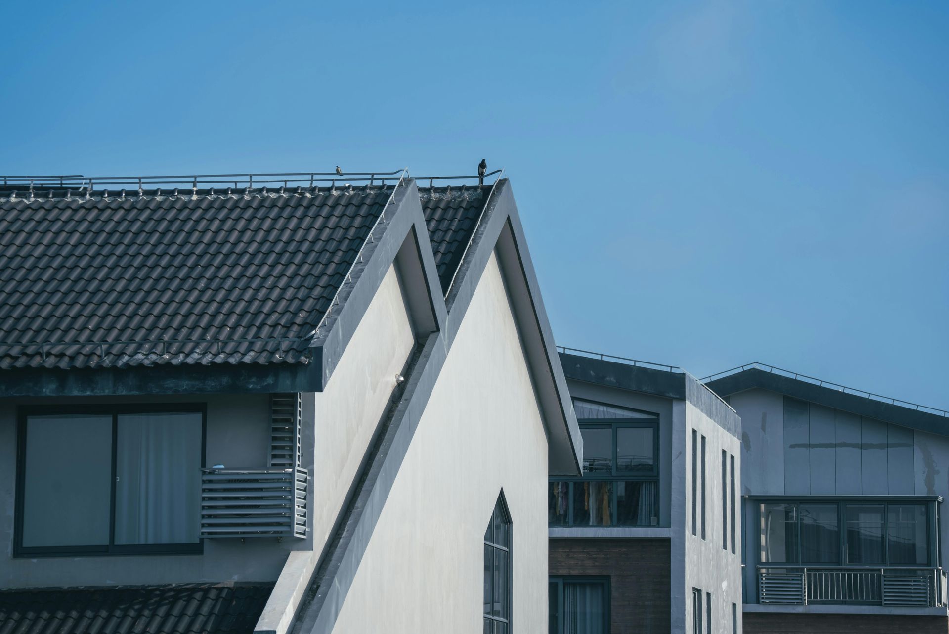 Modern apartment buildings with gray roofs under a clear blue sky