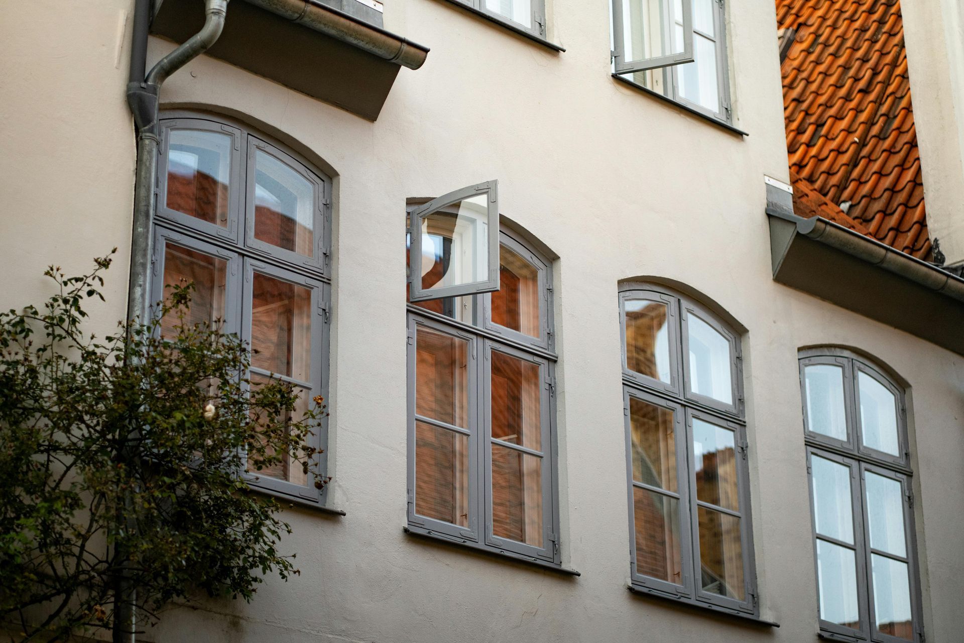 Facade of cream-colored building with arched windows and red-tiled roof edge