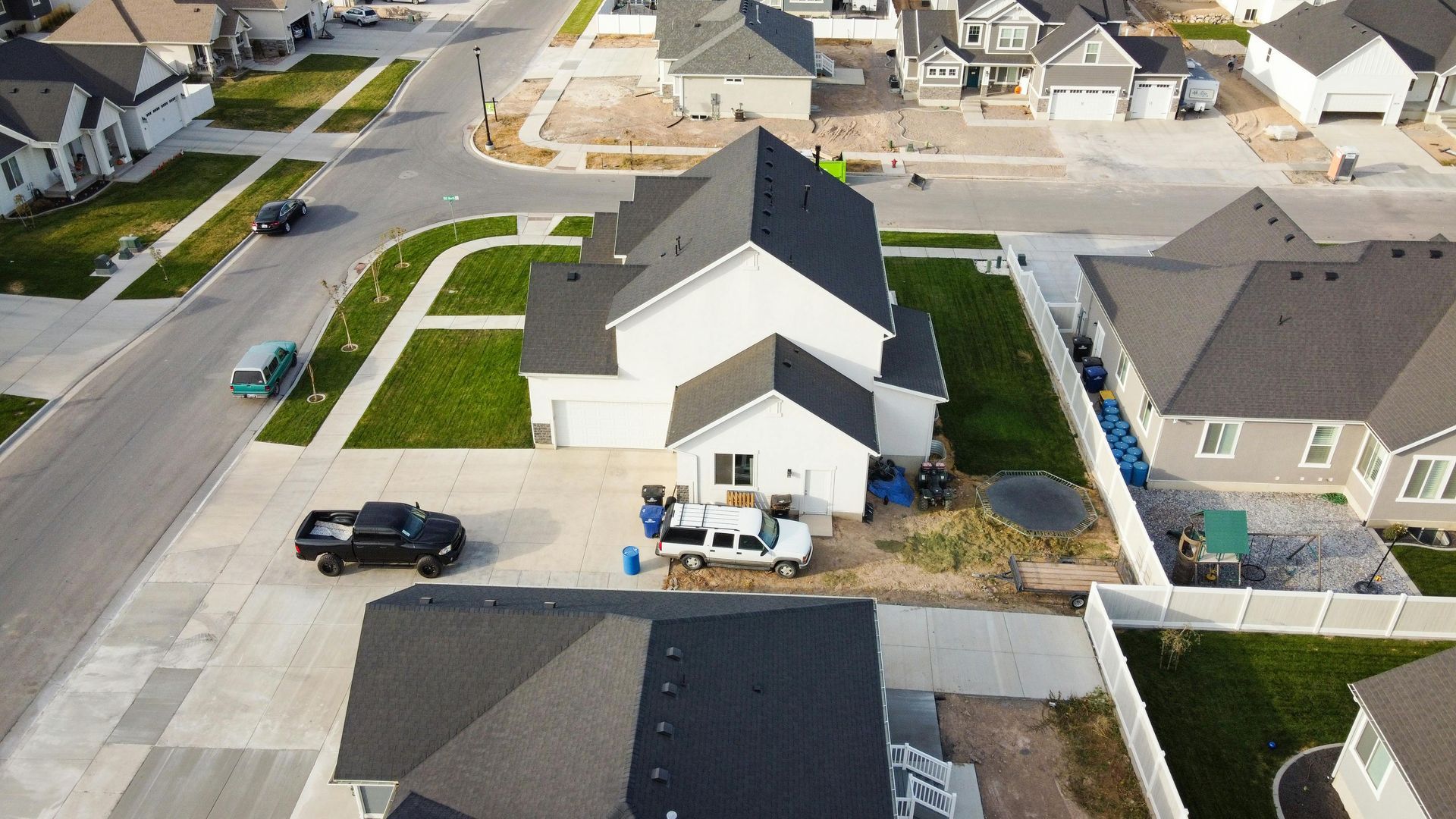 Aerial view of a suburban house with a black SUV in the driveway and workers at the front porch.