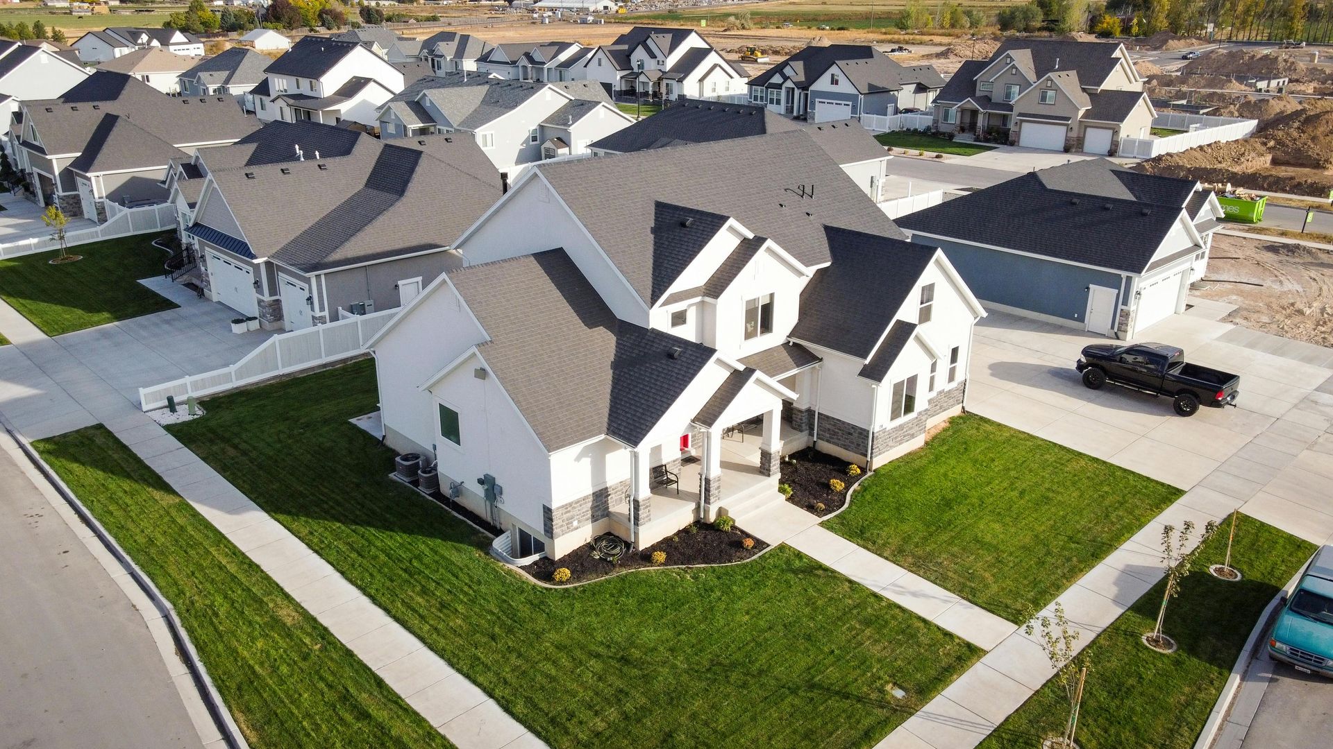 Aerial view of a suburban neighborhood with gray-roofed houses, sidewalks, and green lawns