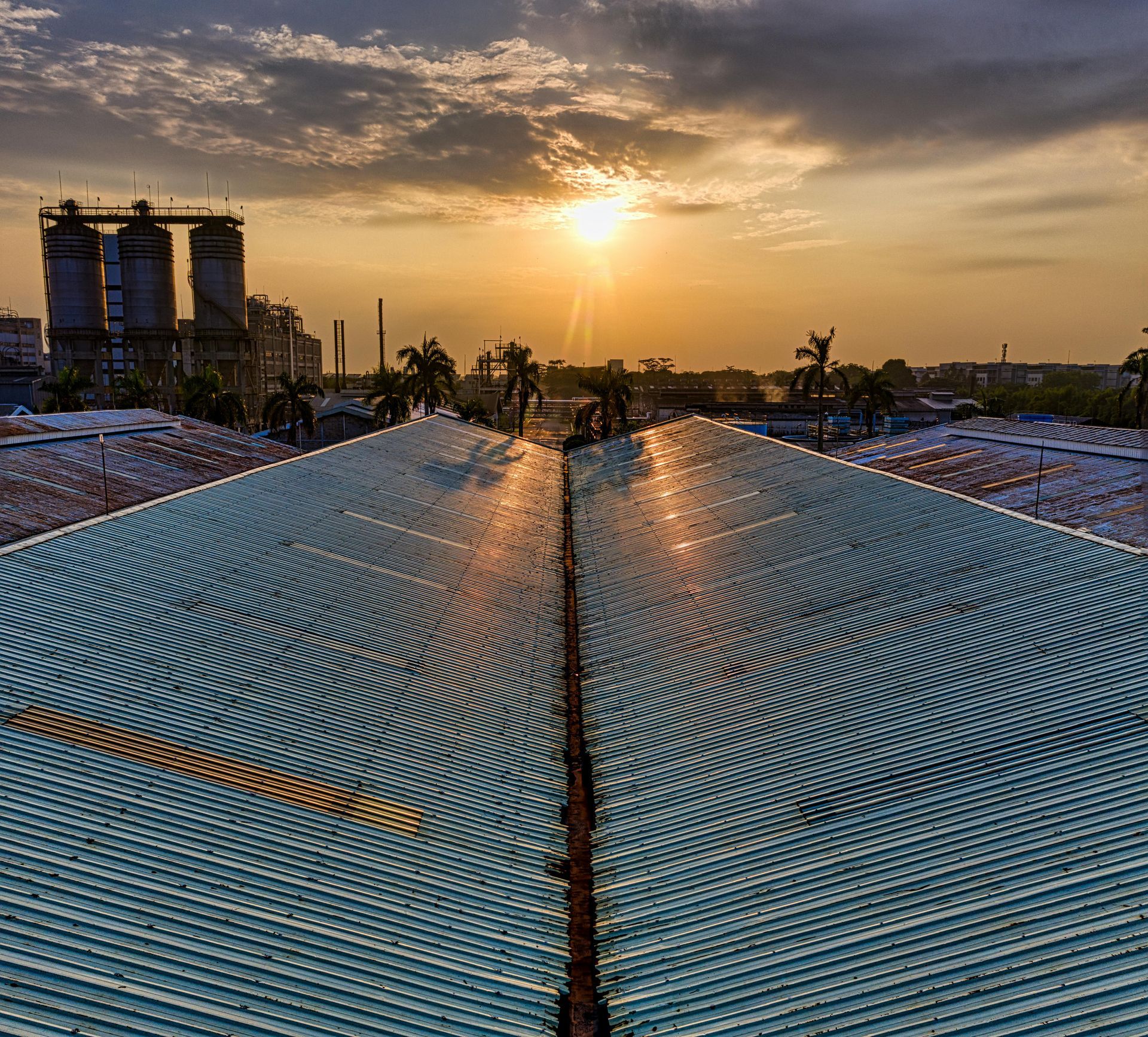 Sunset over a vast blue amphitheater seating area with a central aisle and city skyline in the distance