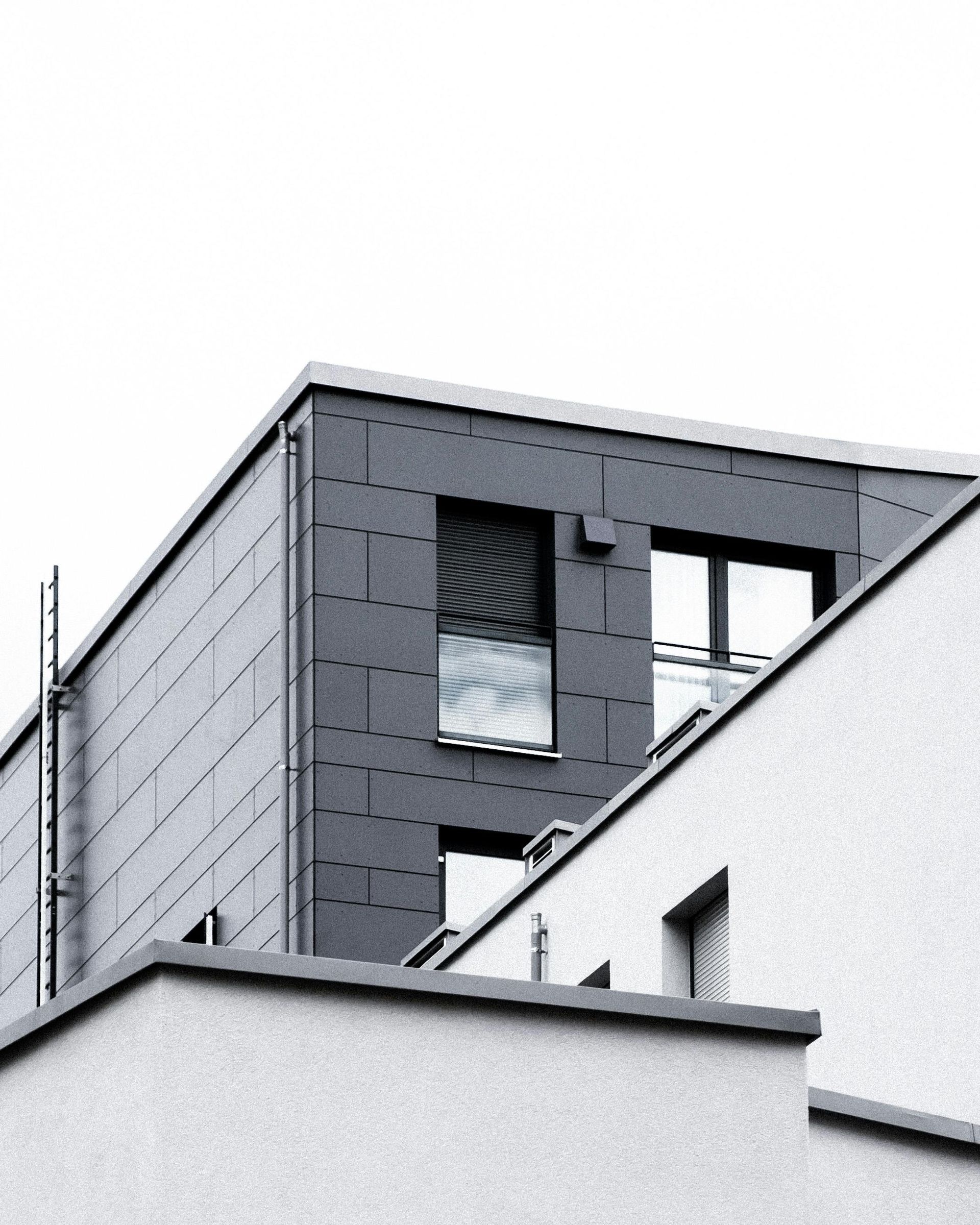 Modern apartment buildings with white and dark gray facades under a cloudy sky