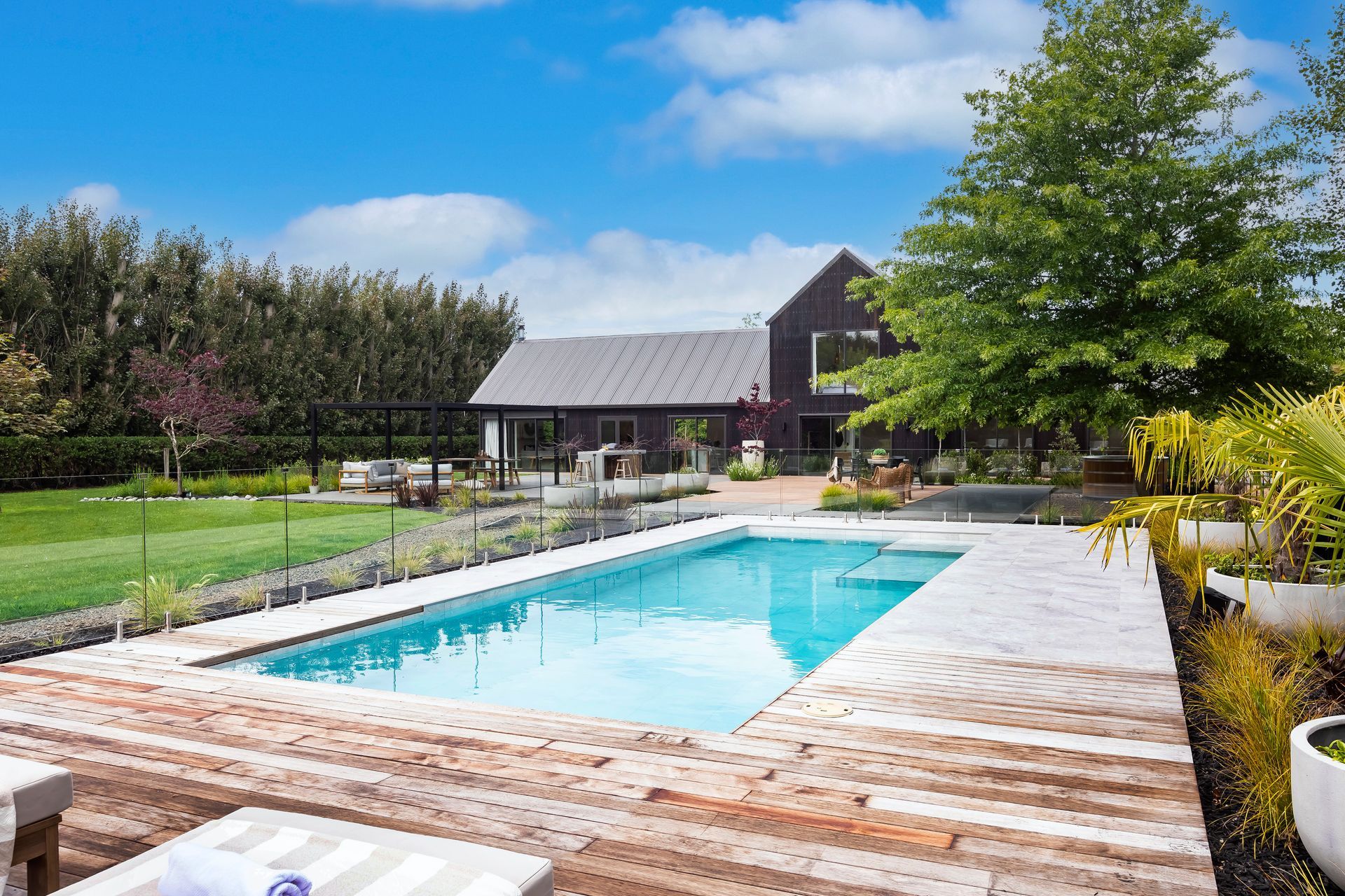 There is a large swimming pool in the backyard of a house.