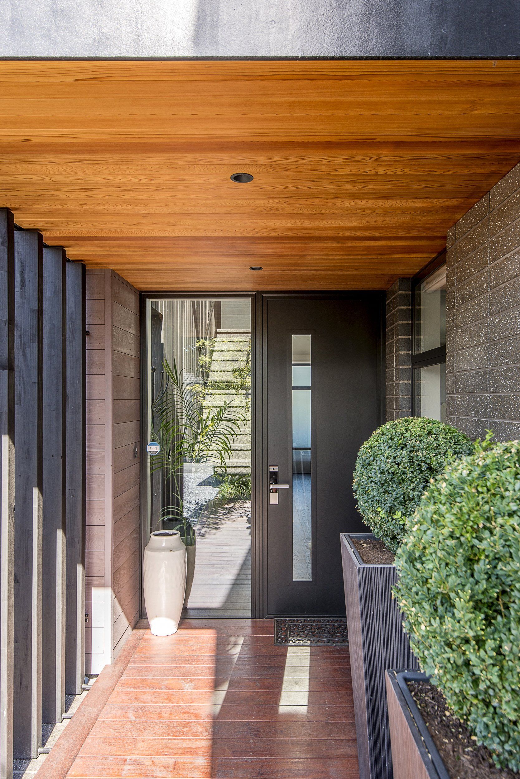 The front door of a house with a wooden ceiling and a glass door.