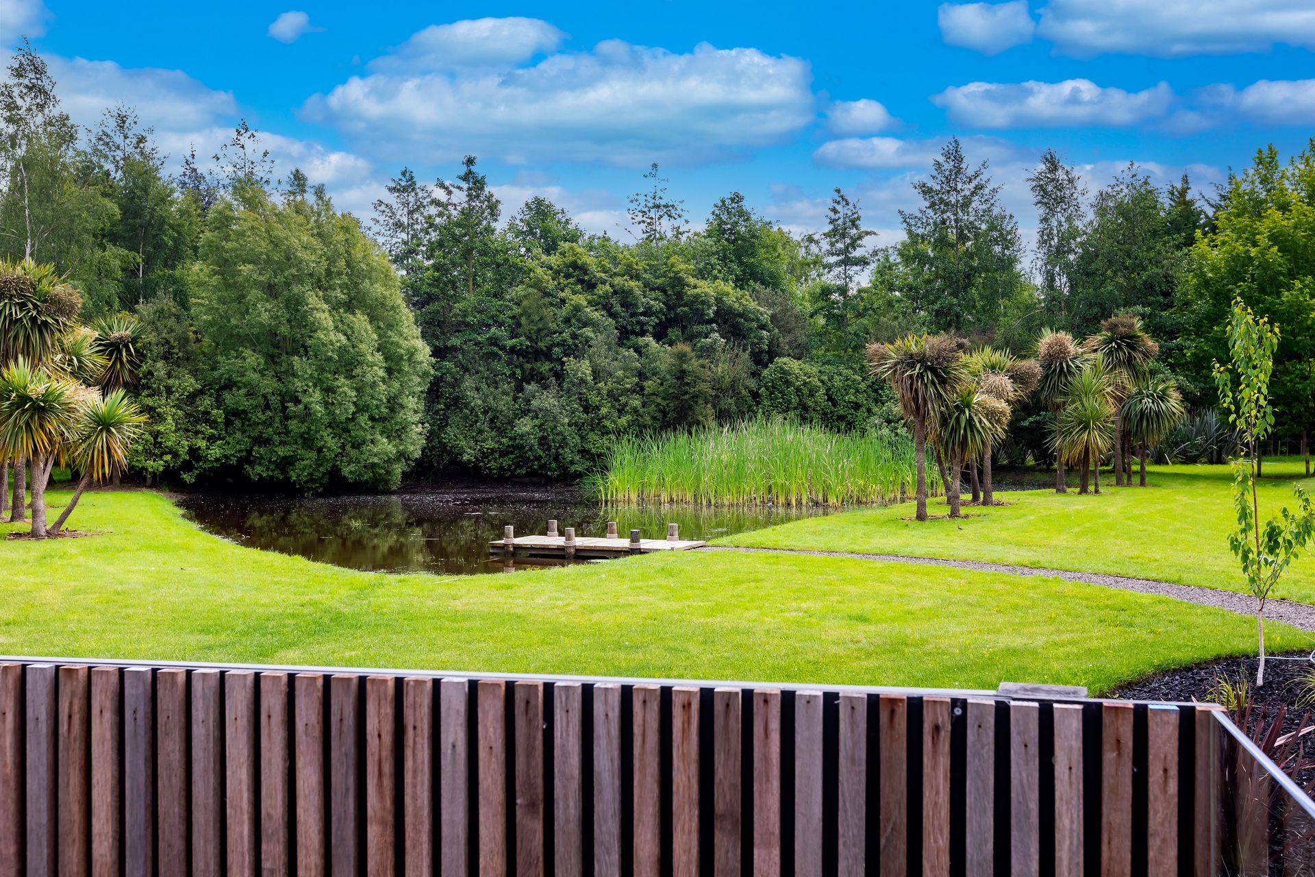 A wooden fence surrounds a pond in a park.