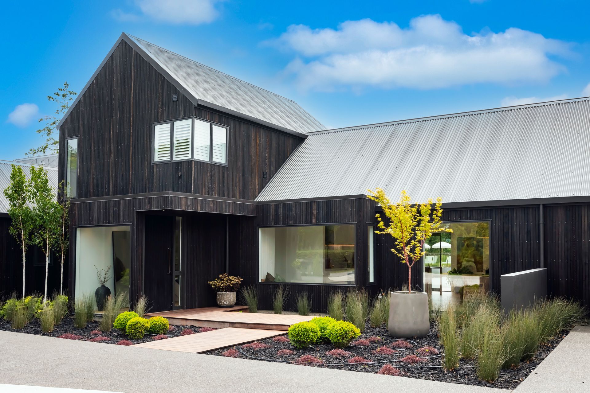 A black barn shaped house with a metal roof
