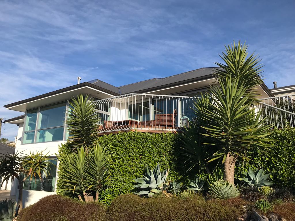 A large house with a balcony is surrounded by trees and bushes.