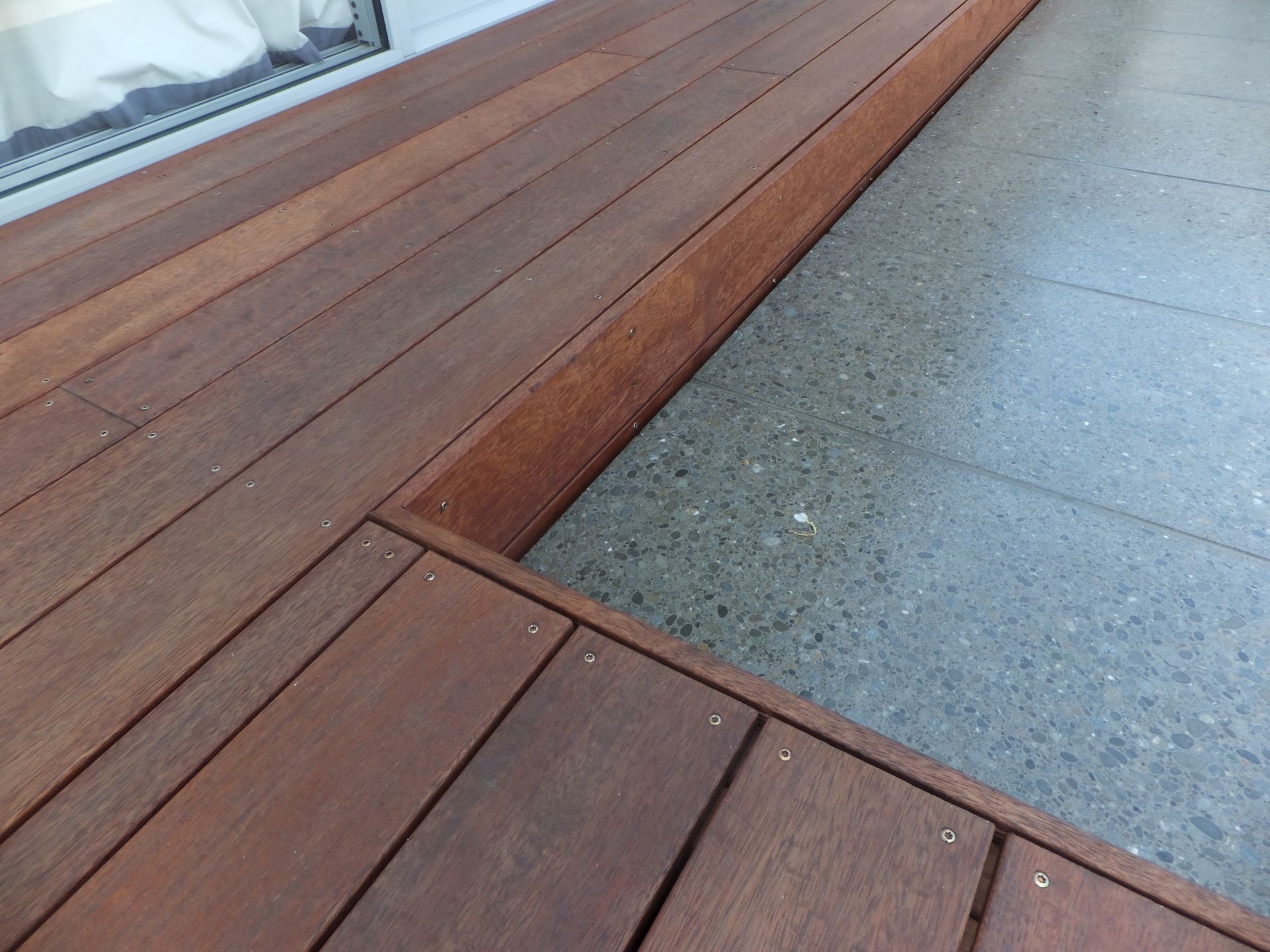 A wooden deck with a concrete floor in the background