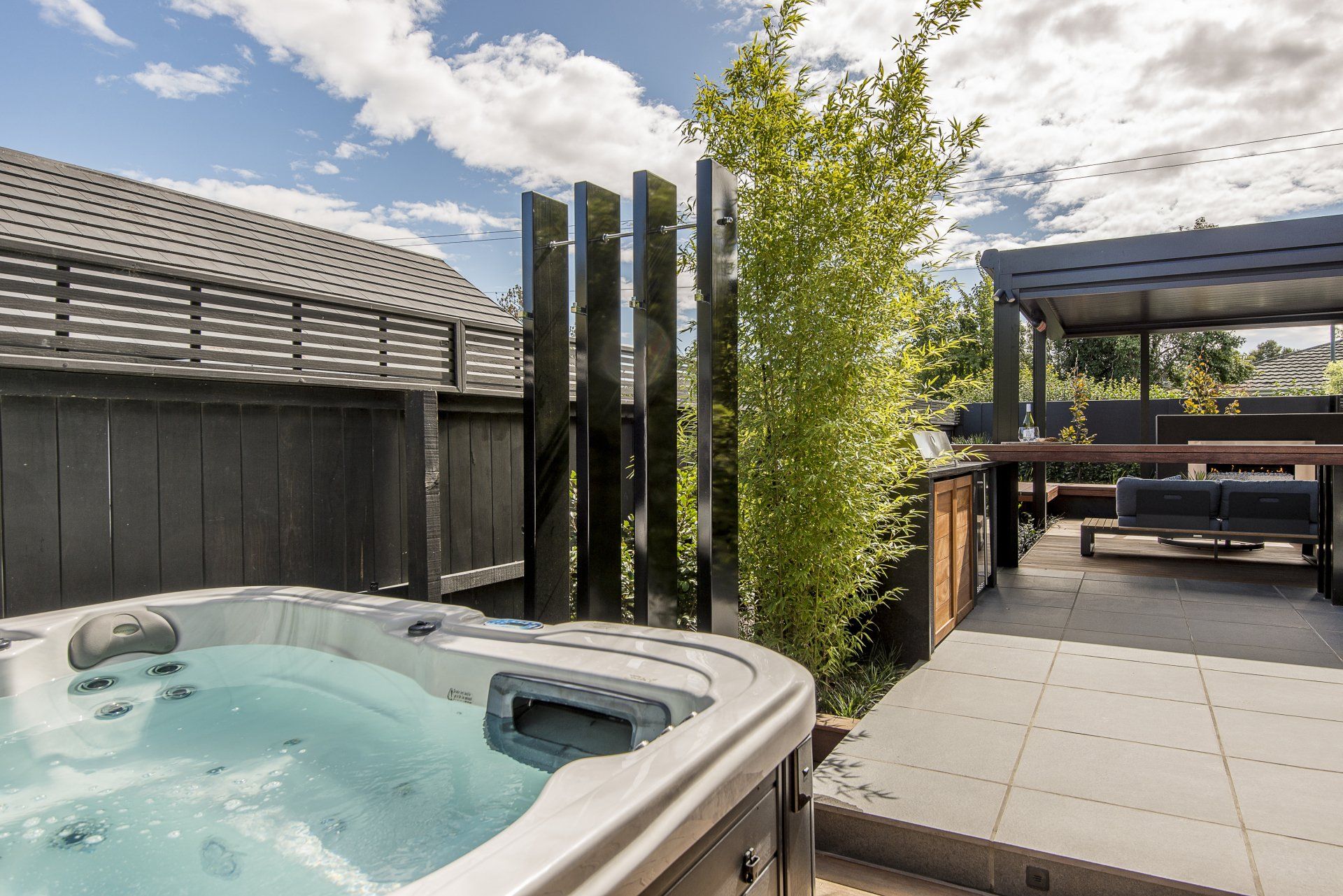 A hot tub is sitting on a patio next to a house.