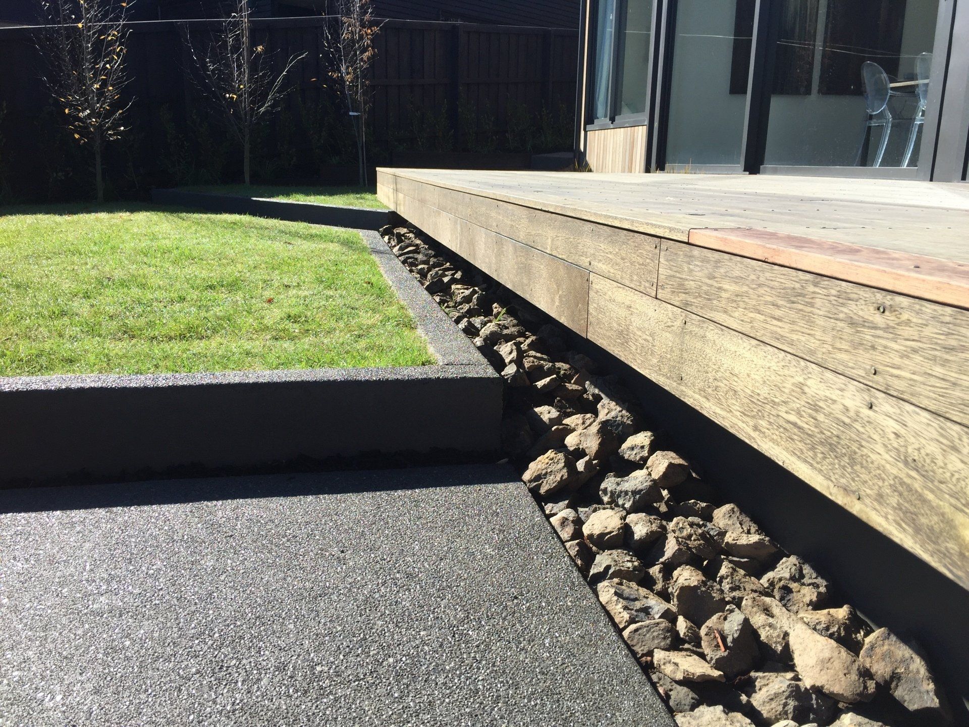 A wooden deck is sitting next to a lush green lawn.