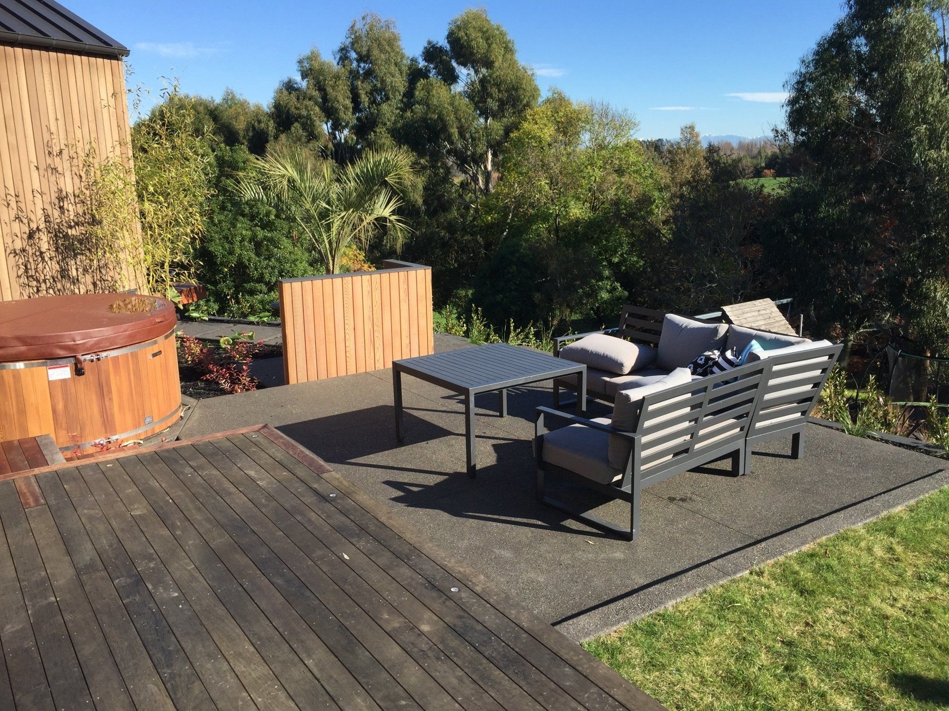 A wooden deck with furniture and a hot tub in the background