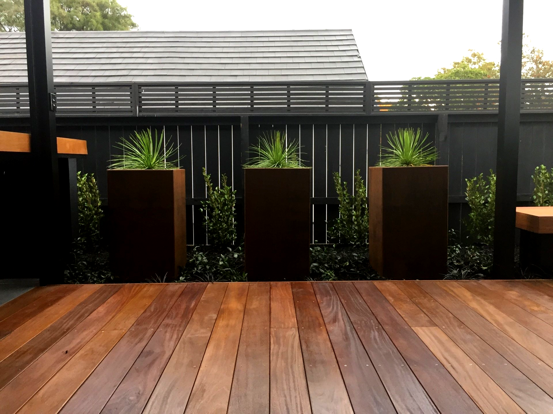 A wooden deck with planters and a fence in the background