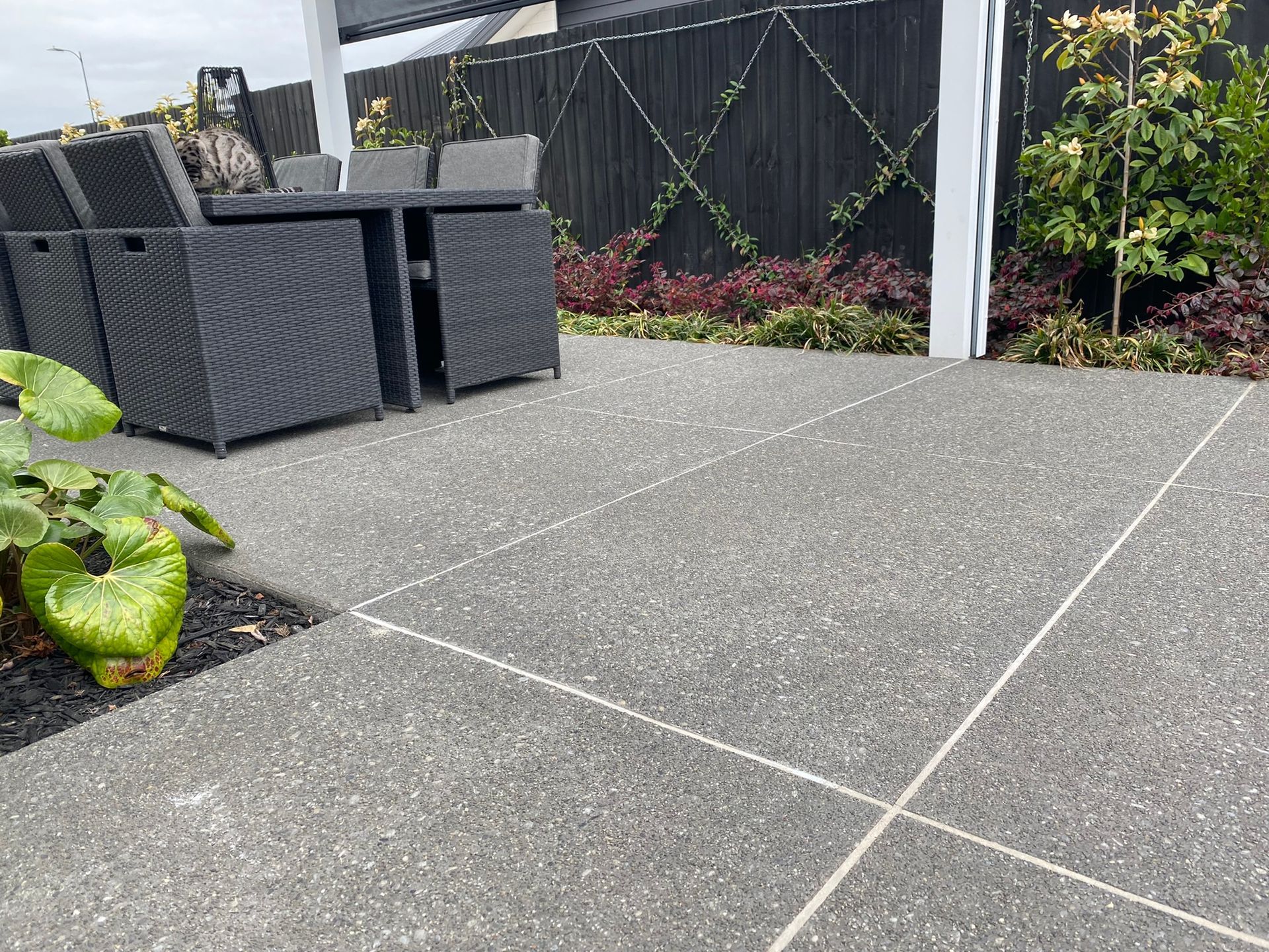A patio with a table and chairs and a fence in the background.
