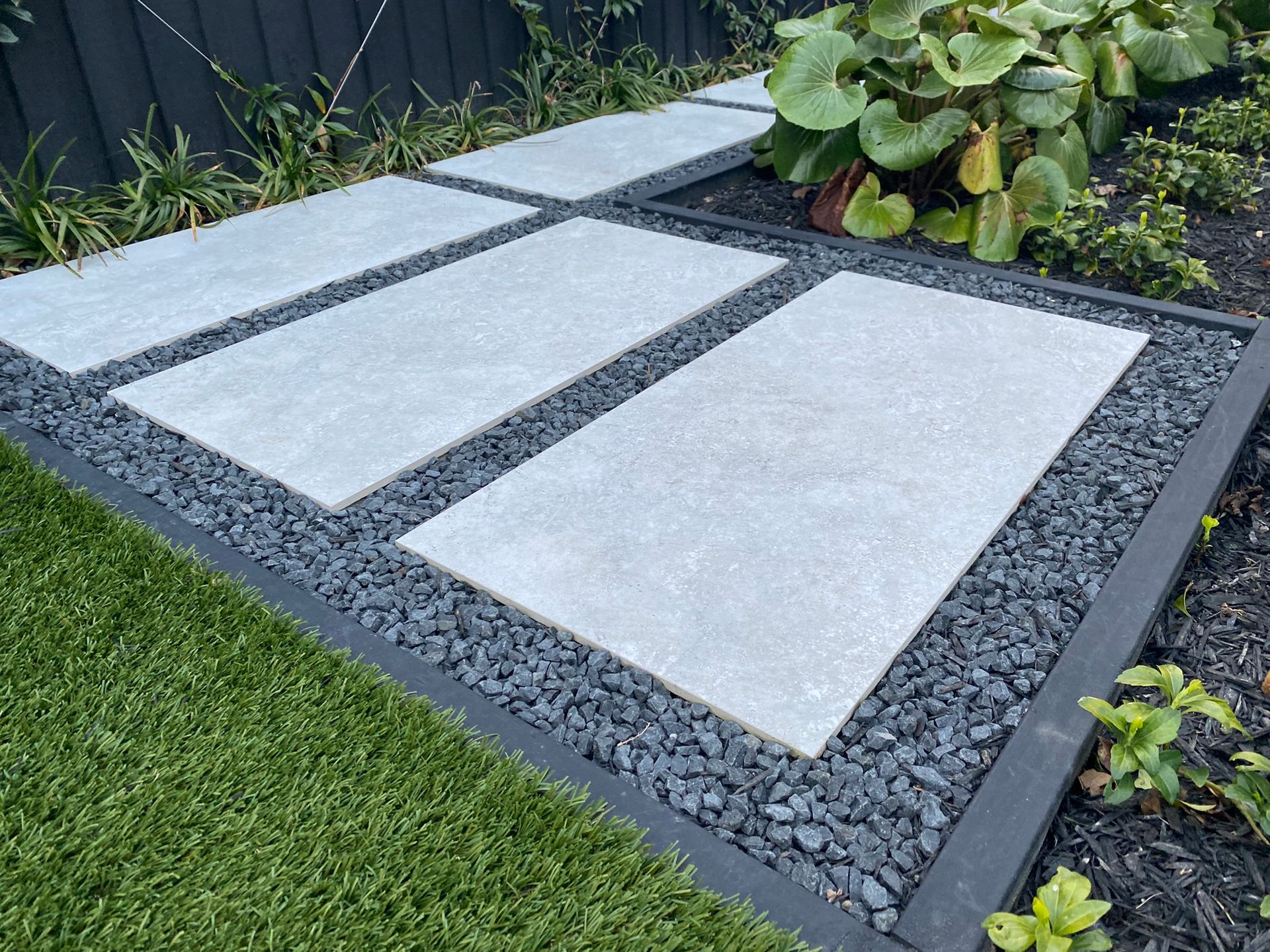 A walkway with concrete slabs and gravel in a garden.