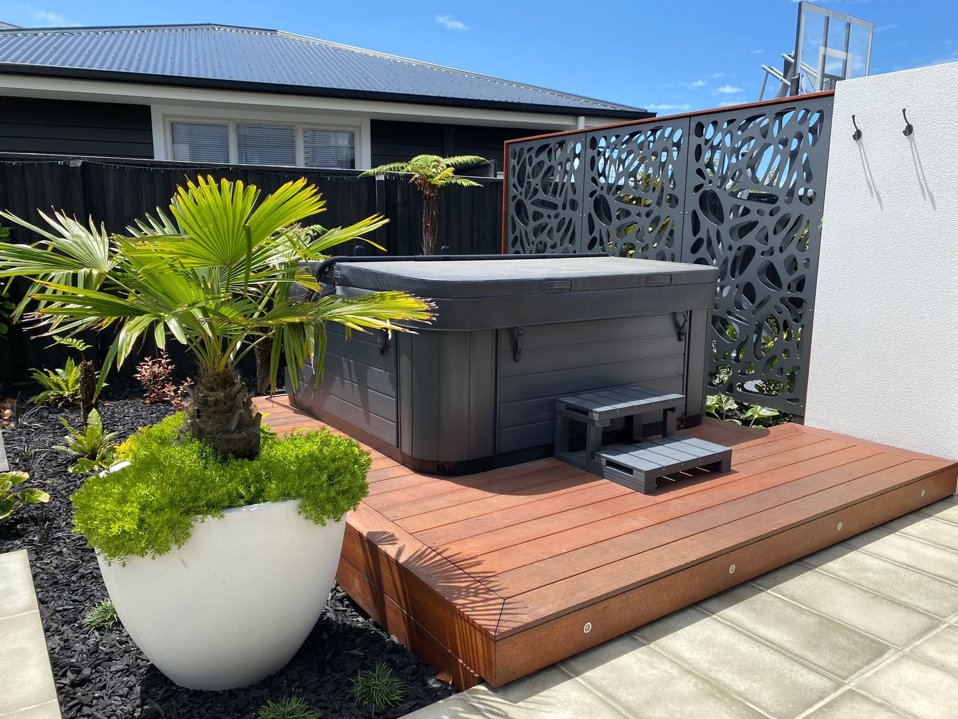 A hot tub is sitting on a wooden deck in front of a house.