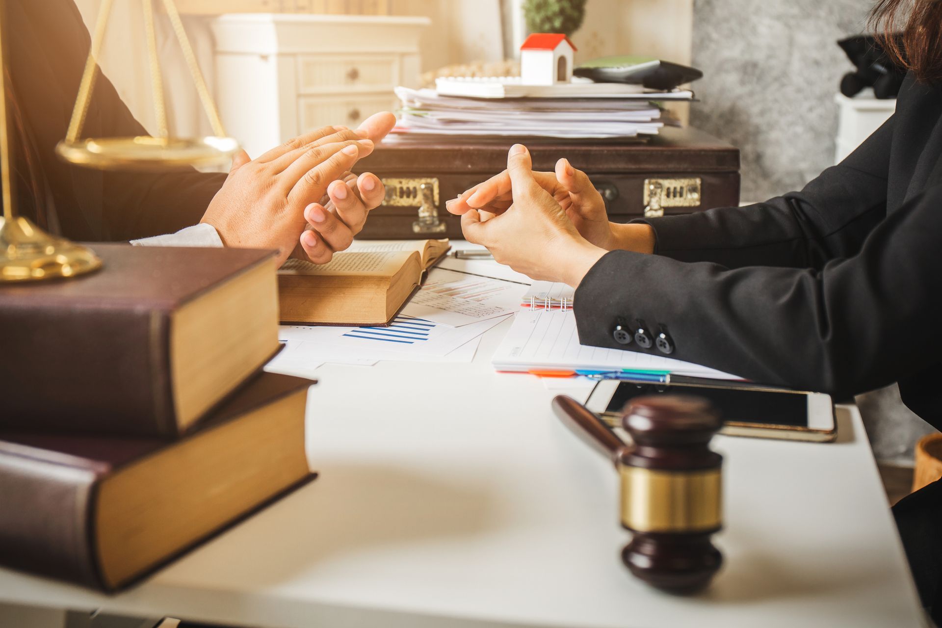 A man and a woman are sitting at a table with books and a gavel.