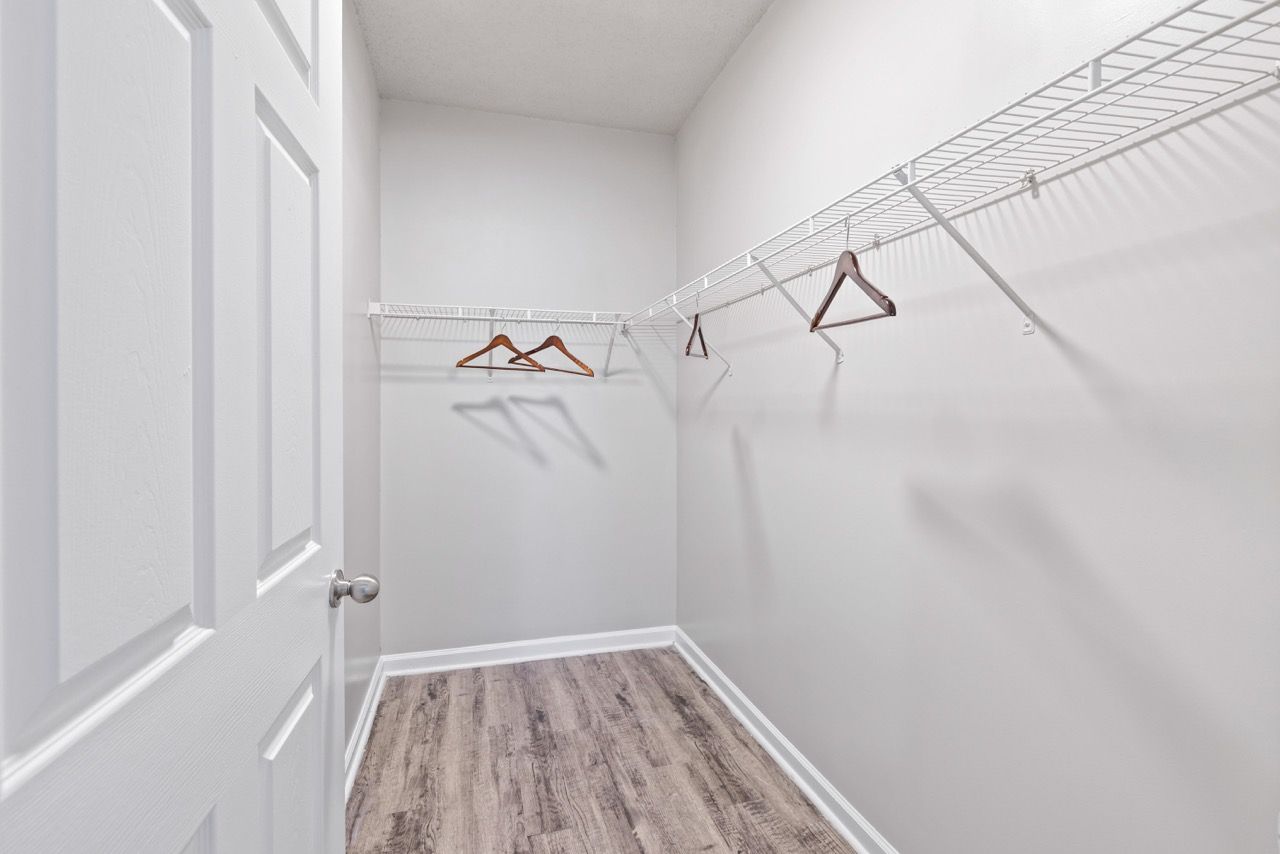 Walk-in closet with white wire shelving and wooden hangers