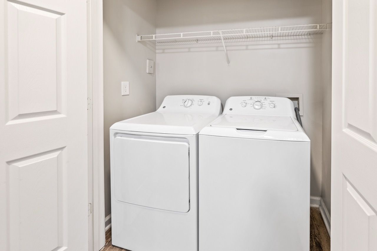 Laundry closet with a front-loading dryer and a top-loading washer under a wire shelf.