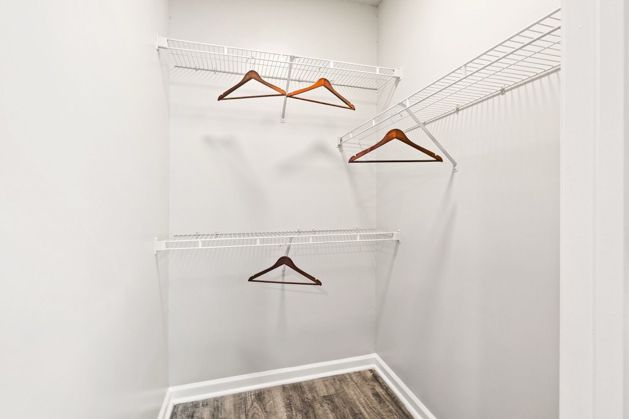 Walk-in closet with white wire shelves and wooden hangers.