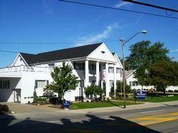 White building with columns and a black roof on a sunny day.