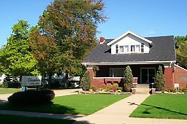 Brick building with a dark roof, green lawn, and sign for a funeral home.