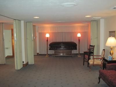 Funeral home chapel with casket, lamps, and chairs.