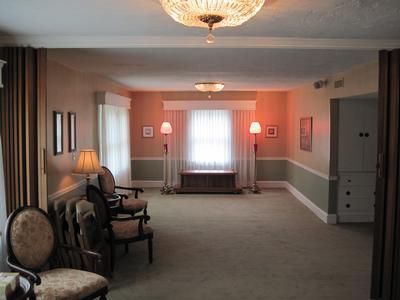 Funeral home interior with chairs, soft lighting, and a window.
