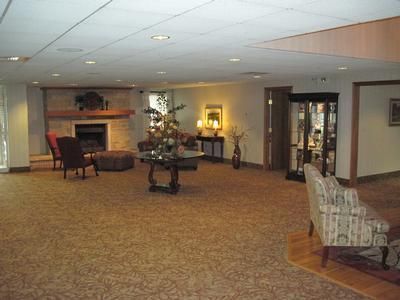 Spacious interior lobby with fireplace, seating, and a display case. Carpeted floors, neutral colors, and recessed lighting.