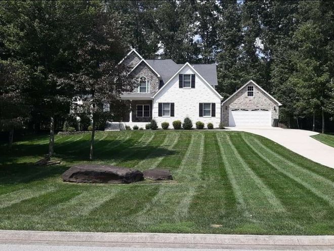 A man is walking down a path in front of a house.