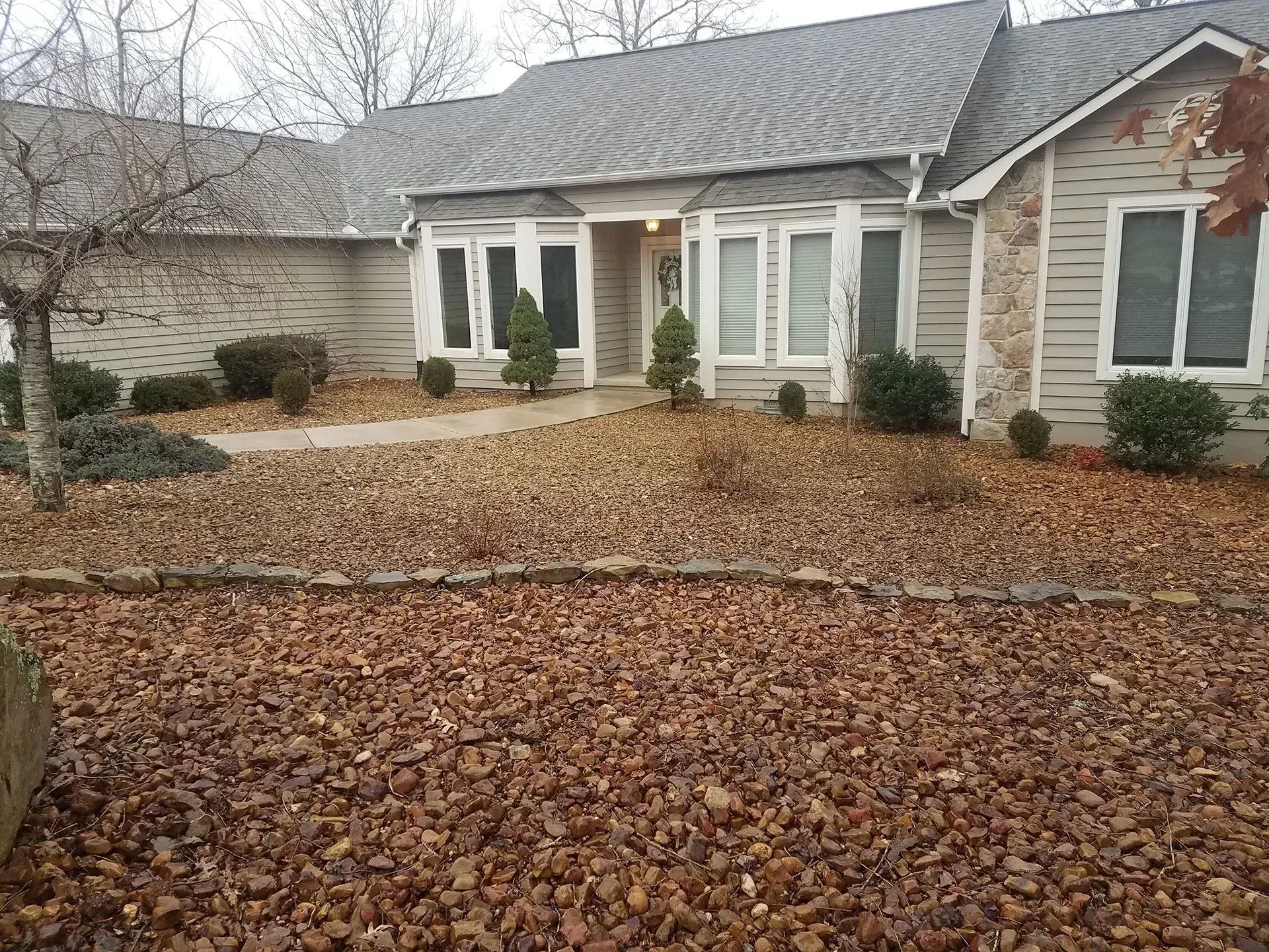 A house with a lot of leaves on the ground in front of it.