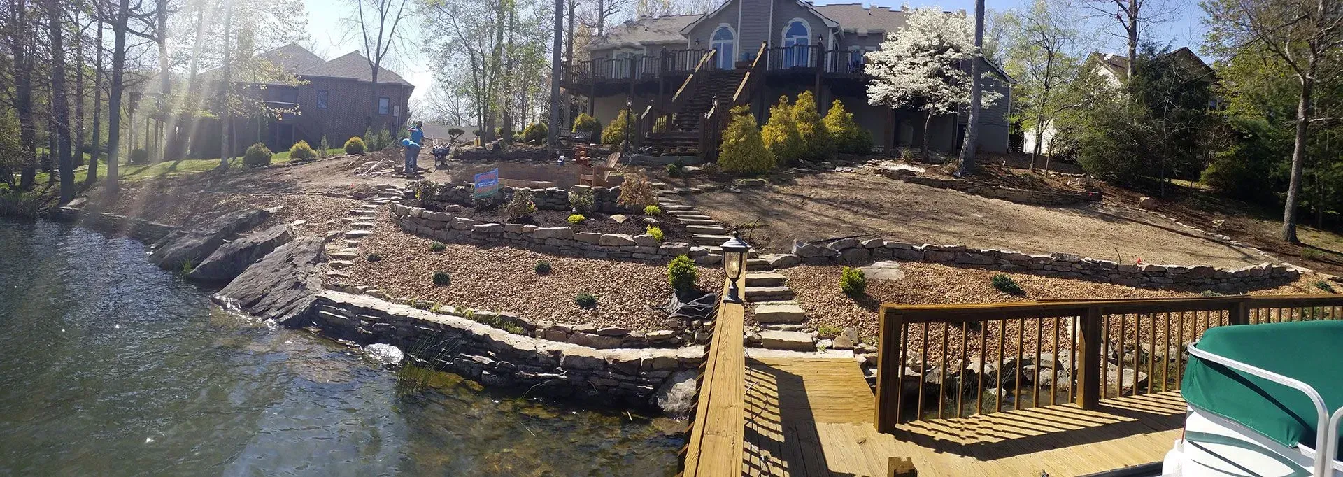 A large house is sitting on top of a hill next to a body of water.