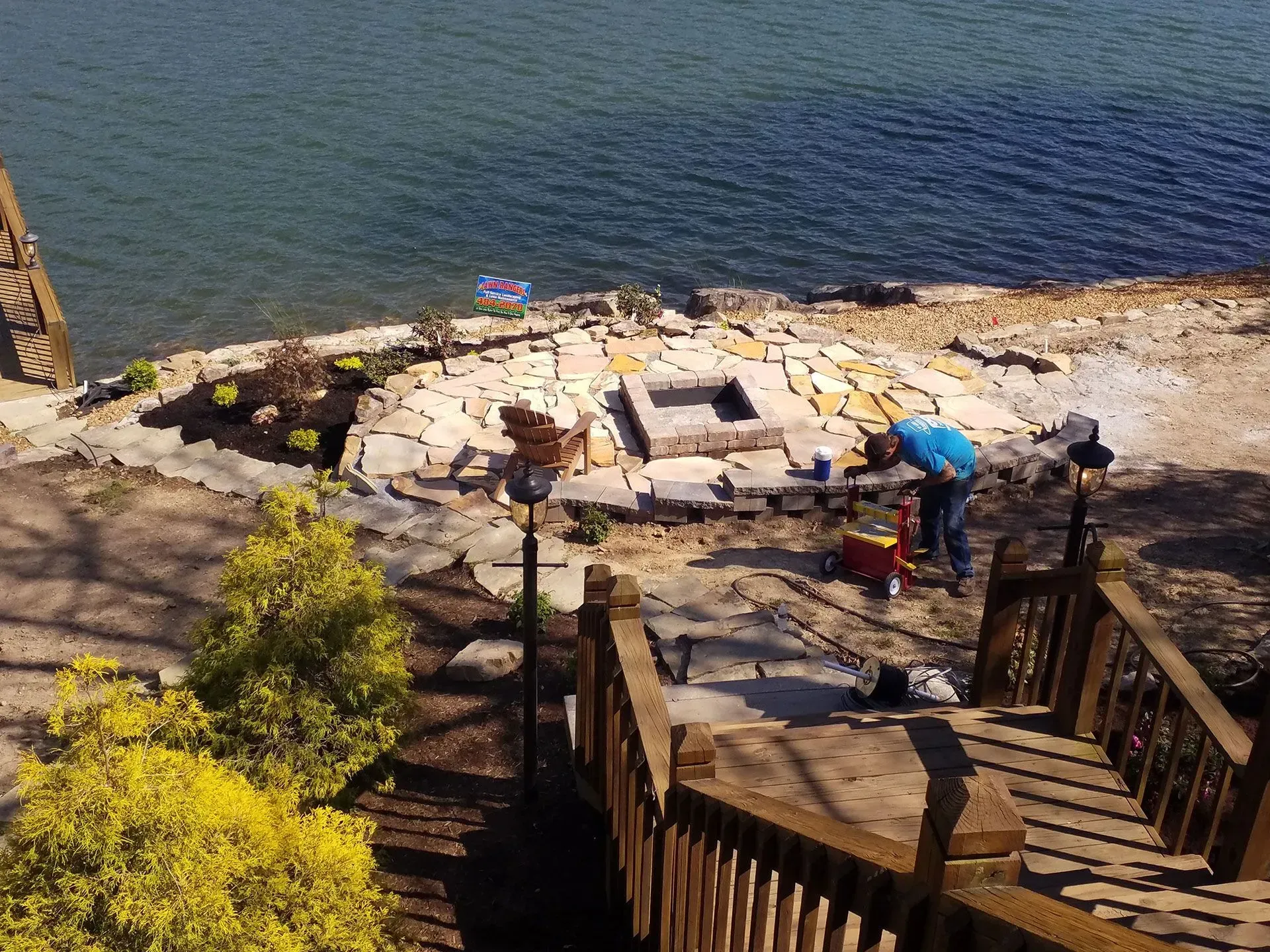 A man is working on a fire pit near the water