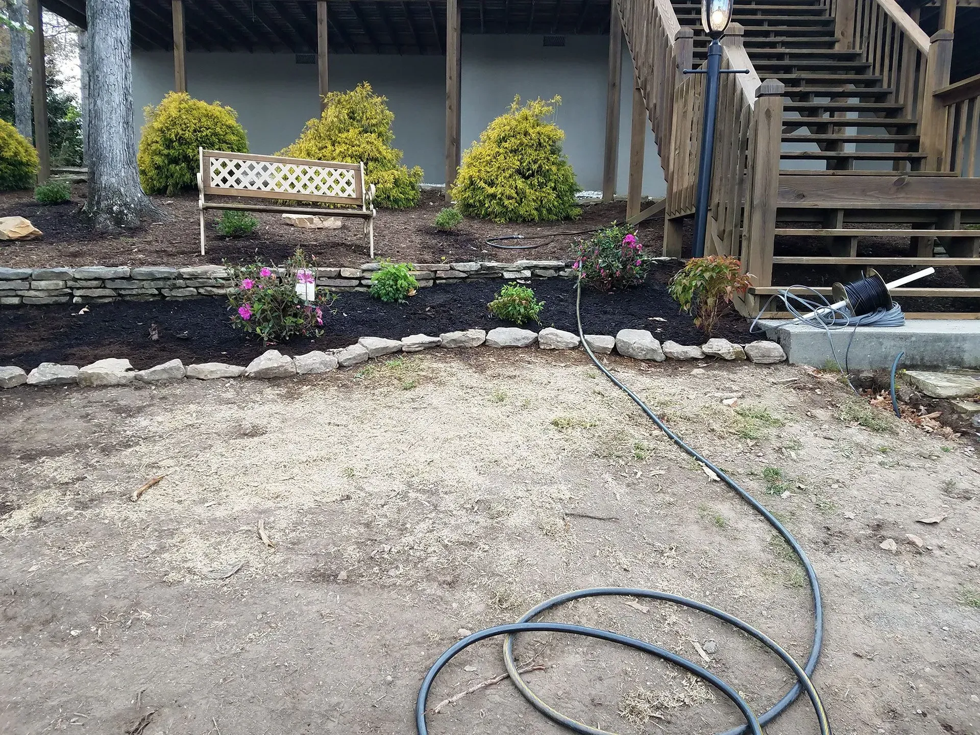 A hose is sitting in the dirt in front of a house.