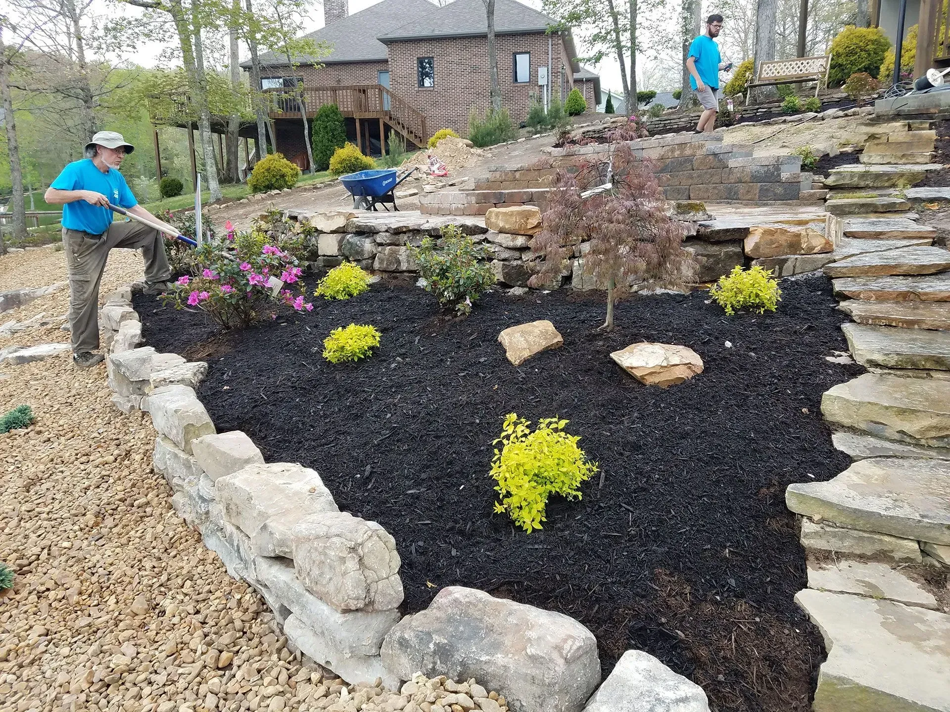 A man is working on a garden in front of a house.