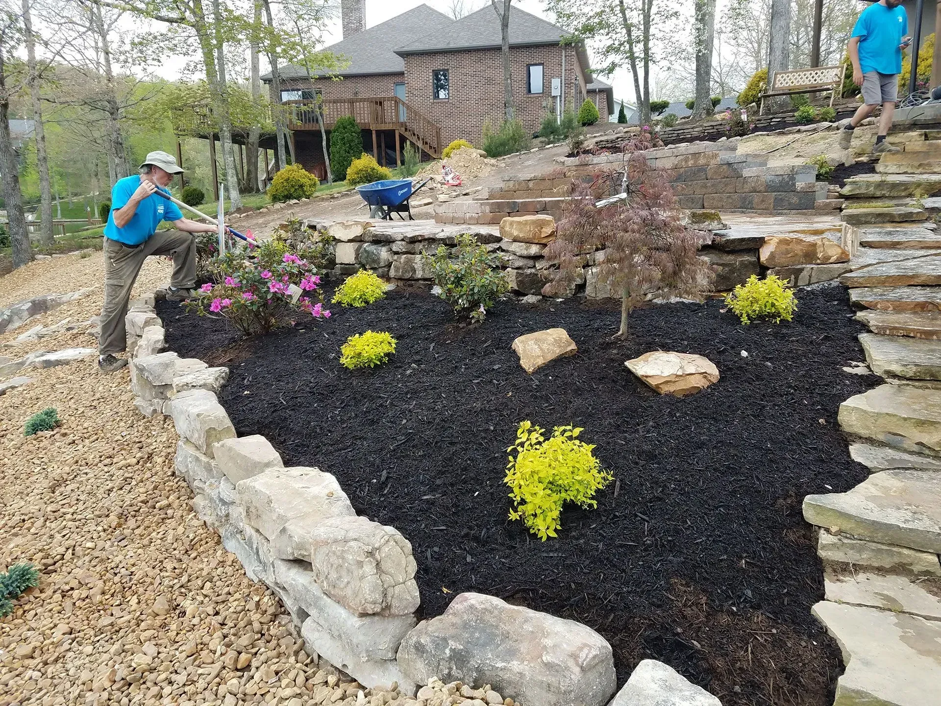 Two men are working on a landscaping project in front of a house.