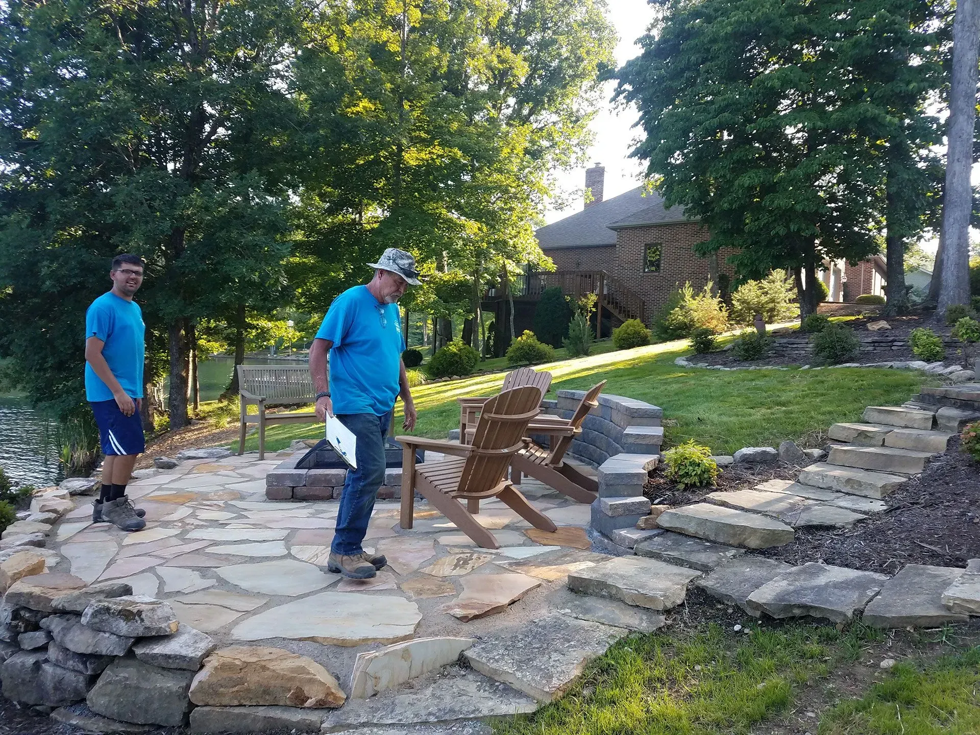 Two men are standing on a stone patio next to a fire pit.