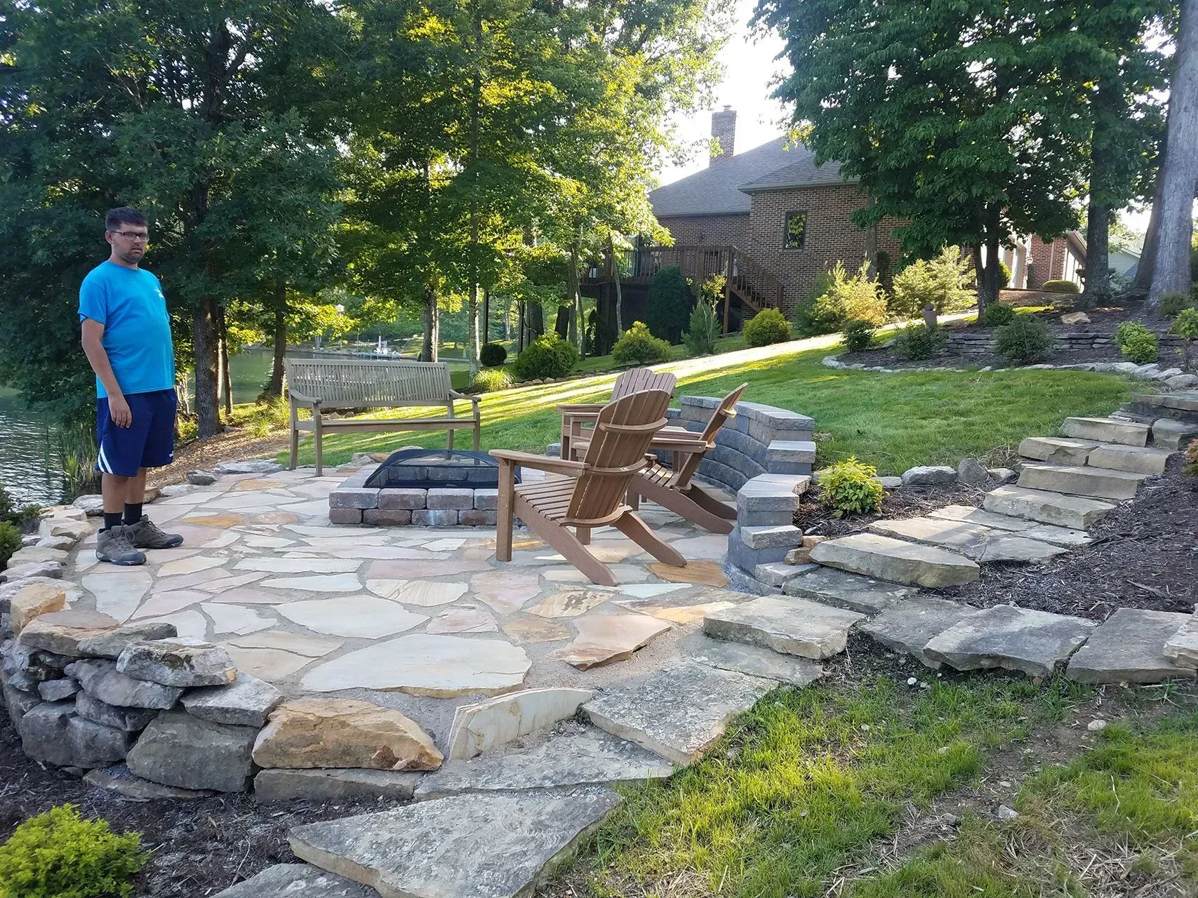 A man is standing next to a fire pit in a backyard.